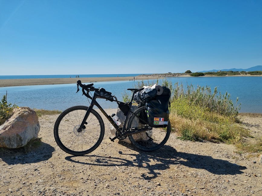 Bicycle with travel gear on a scenic coastal path in France under a clear blue sky.